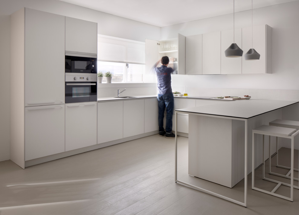 Inspiration for a mid-sized contemporary l-shaped open plan kitchen in Madrid with an undermount sink, flat-panel cabinets, white cabinets, stainless steel appliances and no island.
