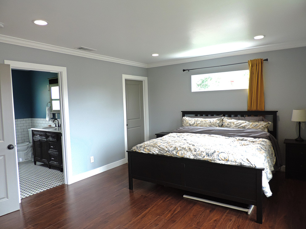 Large arts and crafts master bedroom in Los Angeles with grey walls, laminate floors and brown floor.