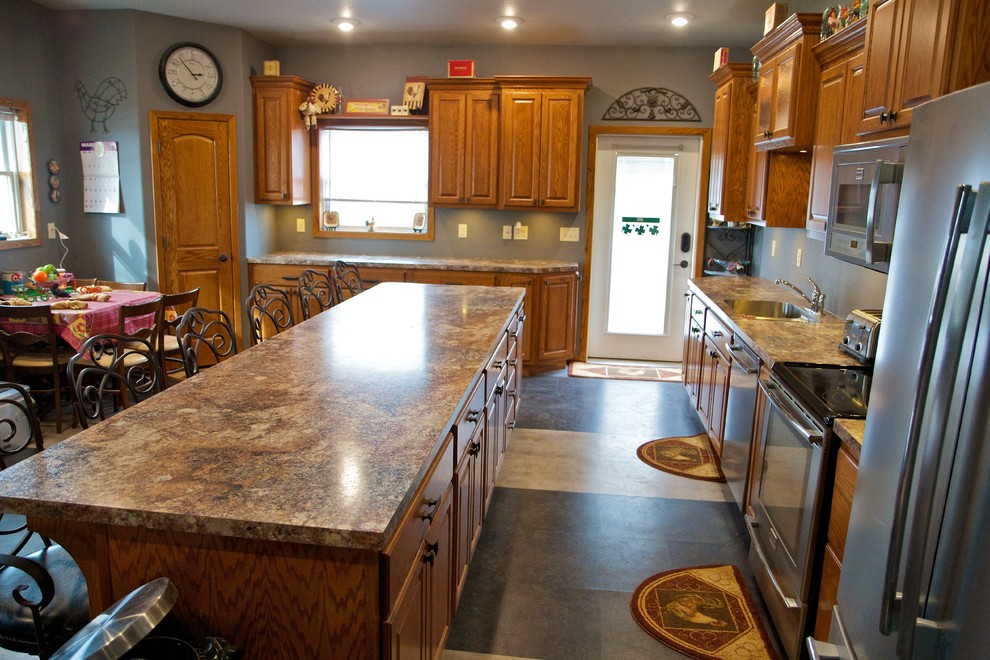 Open concept kitchen - large l-shaped open concept kitchen idea with an undermount sink, raised-panel cabinets, light wood cabinets, laminate countertops, stainless steel appliances and an island