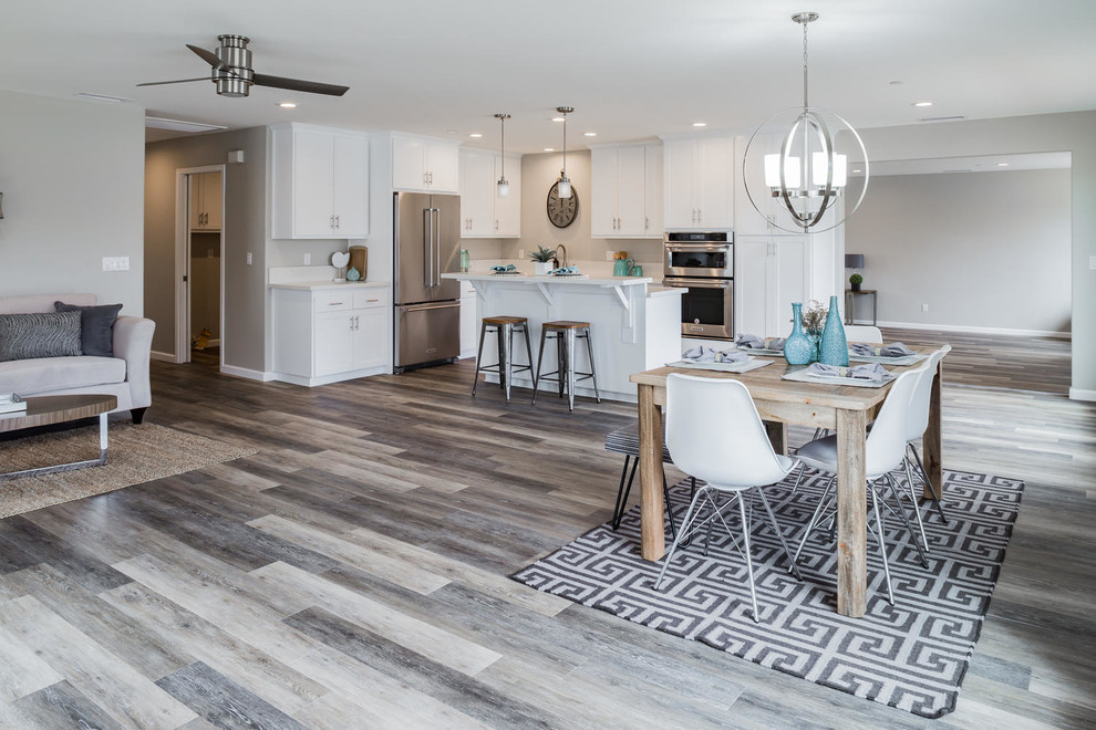 Design ideas for a mid-sized contemporary l-shaped open plan kitchen in San Luis Obispo with an undermount sink, shaker cabinets, white cabinets, quartz benchtops, stainless steel appliances, medium hardwood floors, with island and brown floor.