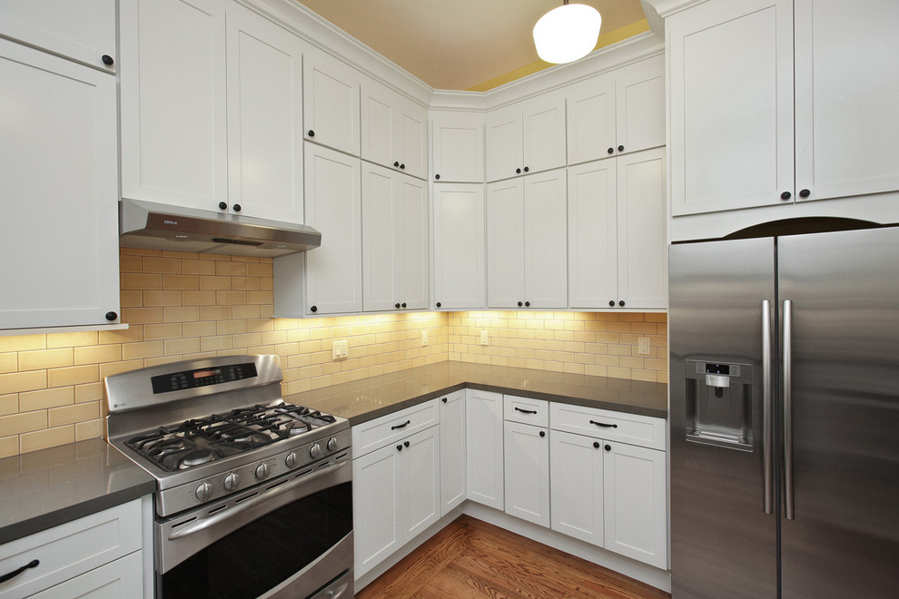 Inspiration for a traditional u-shaped kitchen pantry in San Francisco with an undermount sink, shaker cabinets, white cabinets, quartz benchtops, yellow splashback, glass tile splashback, stainless steel appliances and medium hardwood floors.
