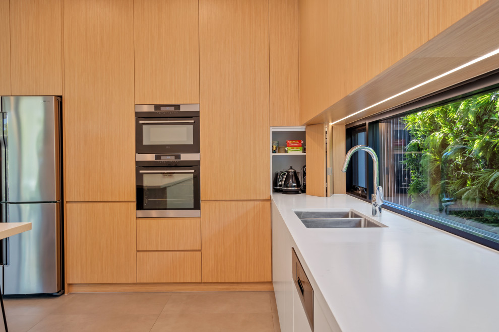 Источник вдохновения для домашнего уюта: параллельная кухня в современном стиле с двойной мойкой, плоскими фасадами, светлыми деревянными фасадами, столешницей из кварцевого агломерата и белой столешницей