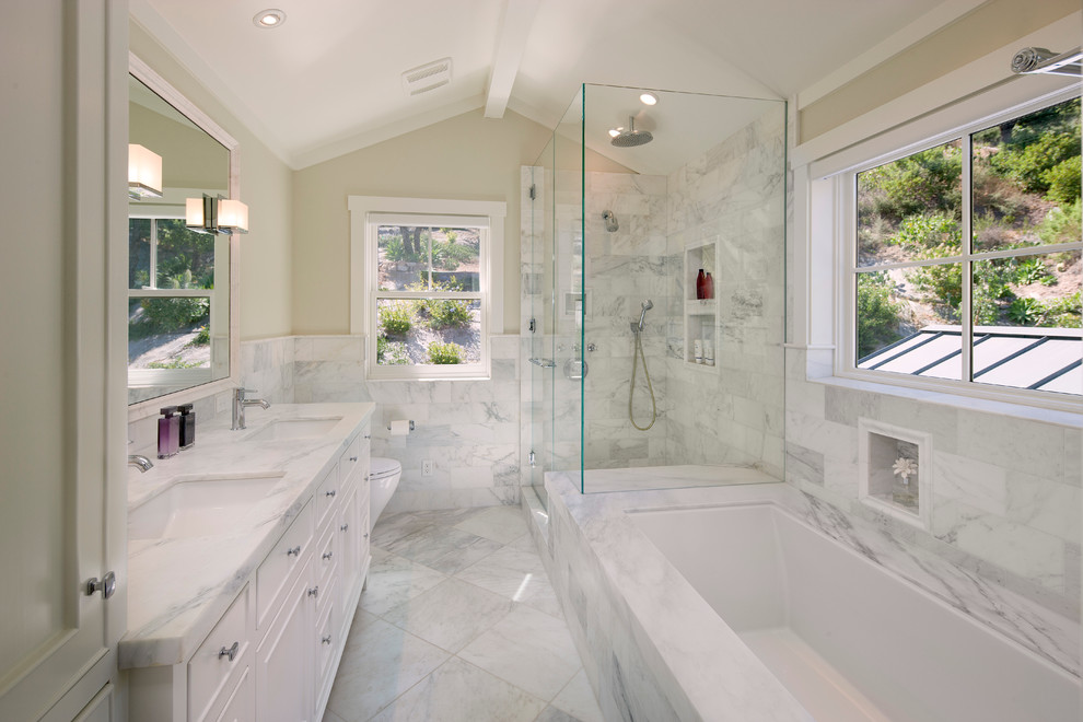 Photo of a large traditional master bathroom in Santa Barbara with white tile, an undermount sink, white cabinets, marble benchtops, a corner shower, beige walls, marble floors, an undermount tub, recessed-panel cabinets, marble, white benchtops and a one-piece toilet.