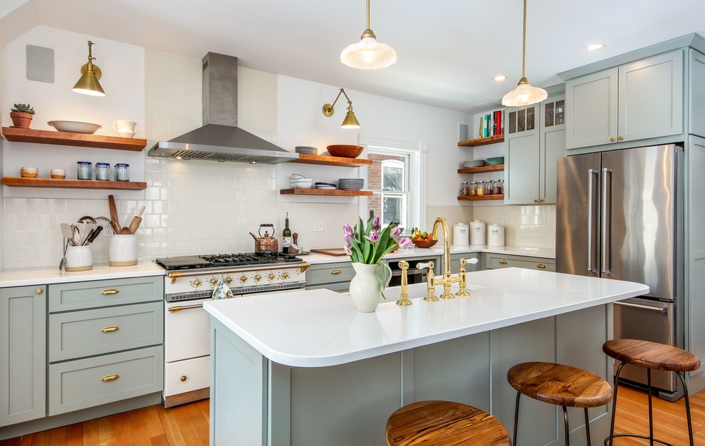 Inspiration for a transitional l-shaped kitchen in Burlington with a farmhouse sink, shaker cabinets, grey cabinets, white splashback, subway tile splashback, stainless steel appliances, medium hardwood floors, with island, brown floor and white benchtop.