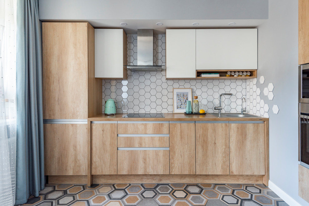 Scandinavian single-wall kitchen in Other with a drop-in sink, flat-panel cabinets, light wood cabinets, white splashback, no island, multi-coloured floor and brown benchtop.