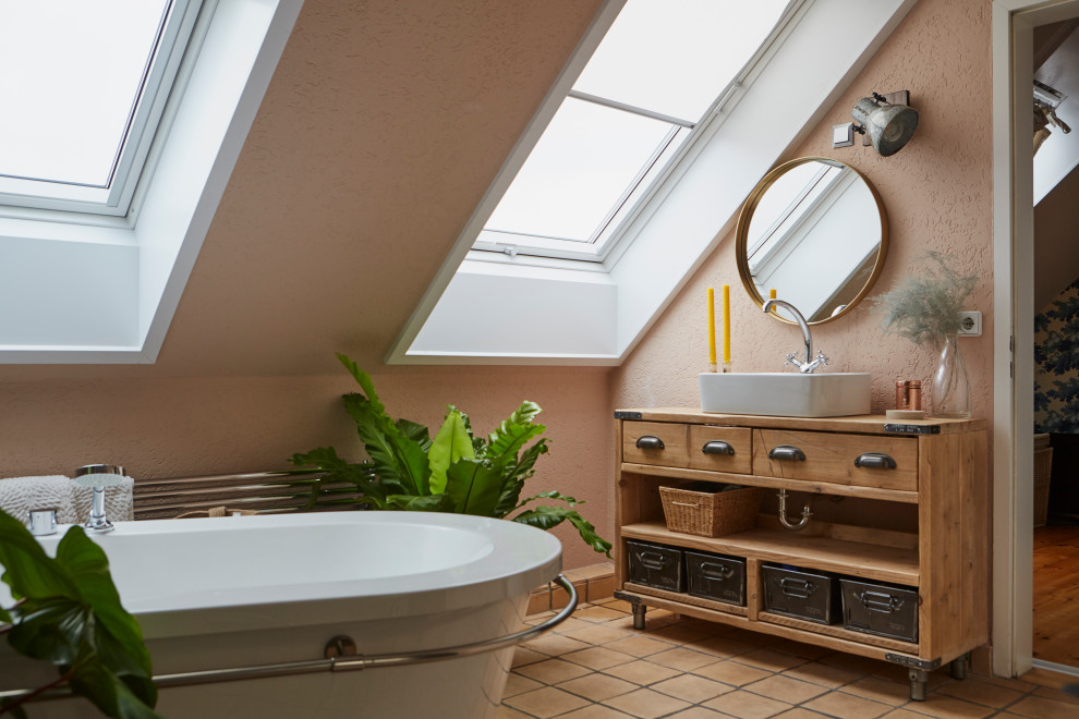 Photo of an eclectic bathroom in London with open cabinets, medium wood cabinets, a freestanding tub, pink walls, a vessel sink, wood benchtops, beige floor, brown benchtops, a single vanity, a freestanding vanity and vaulted.