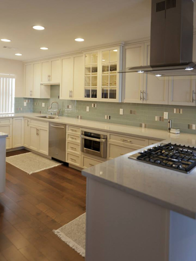 Example of a large transitional u-shaped medium tone wood floor and green floor eat-in kitchen design in Orange County with an undermount sink, beaded inset cabinets, white cabinets, quartz countertops, green backsplash, ceramic backsplash, stainless steel appliances and no island