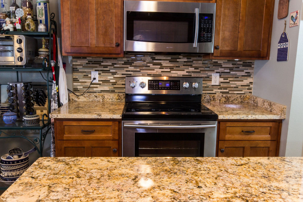 Mid-sized galley cement tile floor and beige floor eat-in kitchen photo with an undermount sink, shaker cabinets, medium tone wood cabinets, granite countertops, multicolored backsplash, glass sheet backsplash, stainless steel appliances, an island and beige countertops