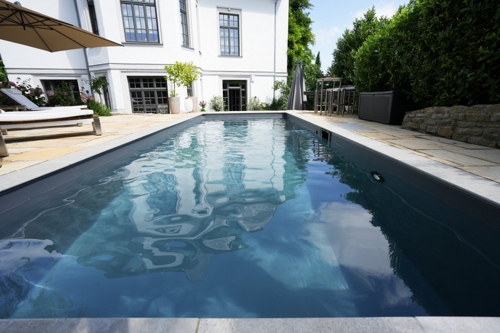 Immagine di una piscina monocorsia minimal rettangolare nel cortile laterale con pavimentazioni in pietra naturale