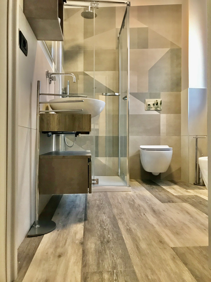 Photo of a small industrial powder room in Milan with flat-panel cabinets, brown cabinets, a wall-mount toilet, porcelain tile, grey walls, laminate floors, a vessel sink, laminate benchtops and brown benchtops.