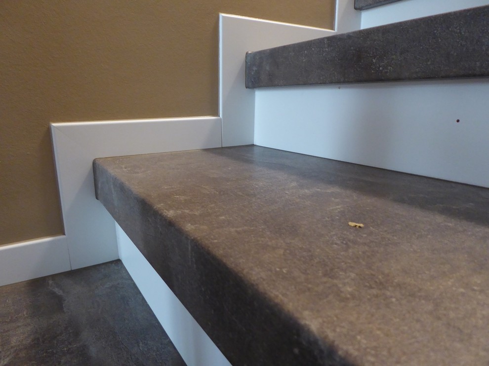 Large contemporary slate l-shaped staircase in Frankfurt with glass risers and wood railing.