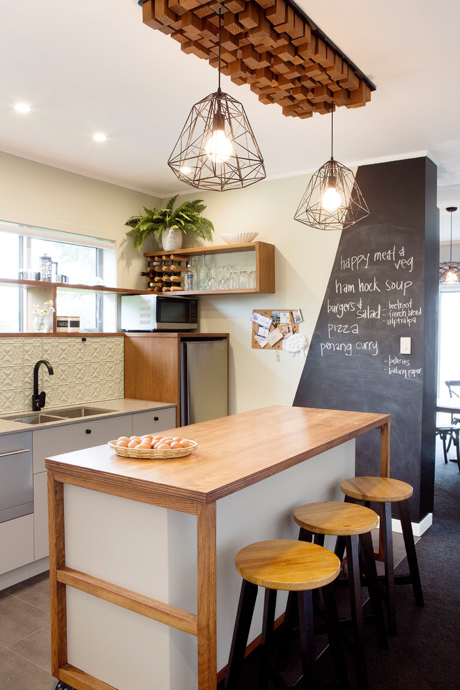 Photo of a mid-sized scandinavian single-wall kitchen in Auckland with a double-bowl sink, wood benchtops, white splashback, stainless steel appliances and with island.