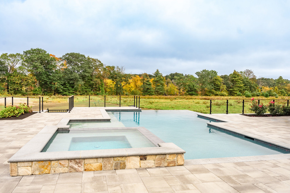 Großer Moderner Infinity-Pool hinter dem Haus in individueller Form mit Natursteinplatten in Boston