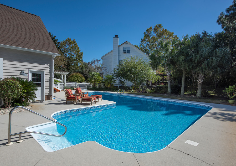 Design ideas for a large traditional backyard l-shaped lap pool in Raleigh with concrete slab.