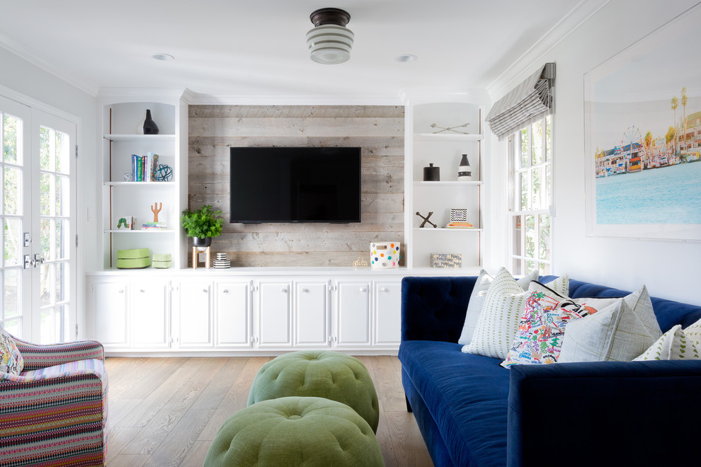 Photo of a beach style gender-neutral kids' room in Orange County with white walls and light hardwood floors.