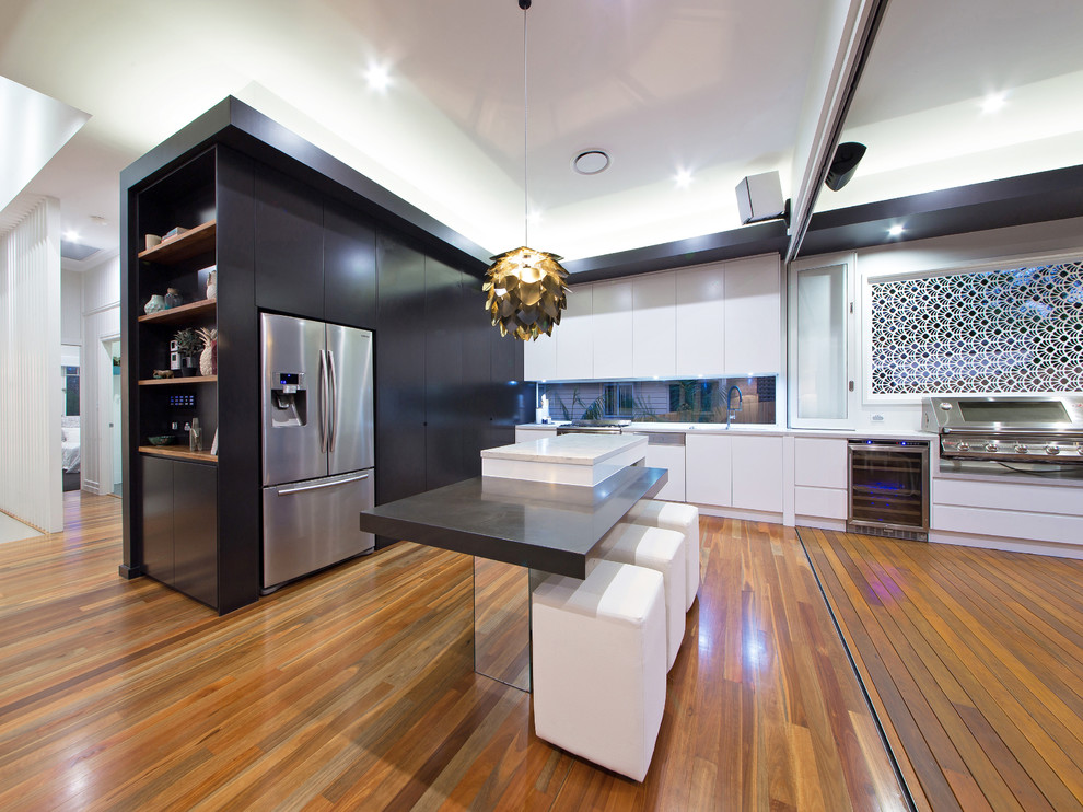 This is an example of a large contemporary single-wall eat-in kitchen in Brisbane with black cabinets, marble benchtops, glass sheet splashback, medium hardwood floors and with island.