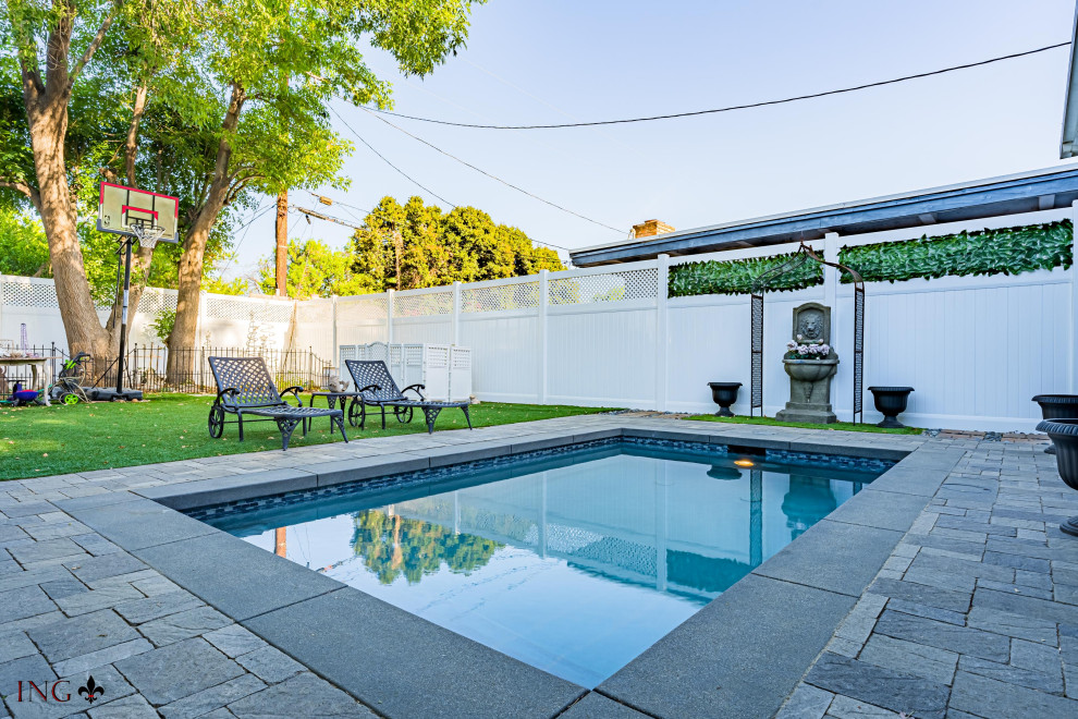 Imagen de piscina natural actual de tamaño medio rectangular en patio trasero con privacidad y adoquines de ladrillo