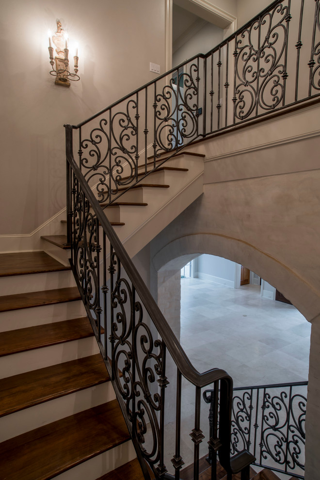Photo of an expansive country wood l-shaped staircase in New Orleans with painted wood risers and metal railing.