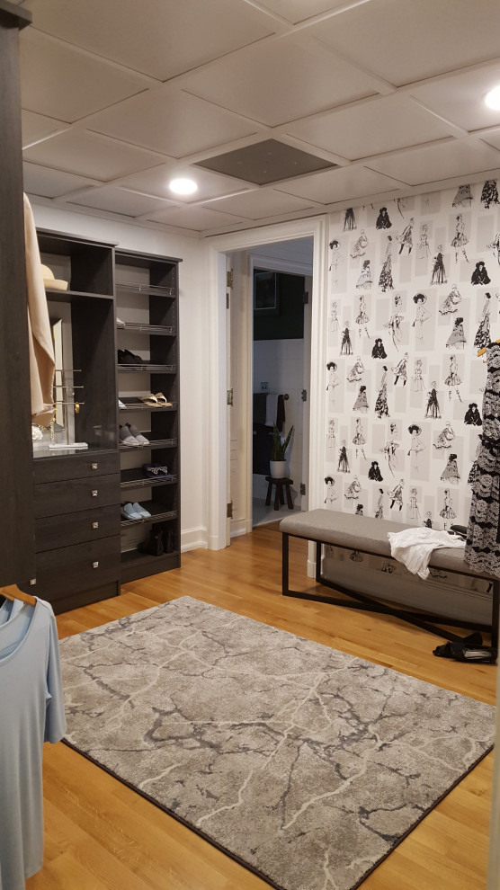 Photo of a medium sized classic walk-in wardrobe for women in New York with flat-panel cabinets, dark wood cabinets, light hardwood flooring and a coffered ceiling.