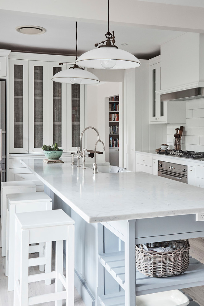 Inspiration for a mid-sized traditional u-shaped kitchen pantry in Sydney with a farmhouse sink, shaker cabinets, white cabinets, marble benchtops, white splashback, subway tile splashback, stainless steel appliances, light hardwood floors and with island.