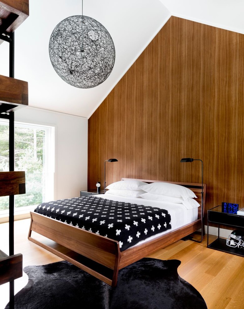 Photo of a modern guest bedroom in New York with brown walls, light hardwood floors and beige floor.