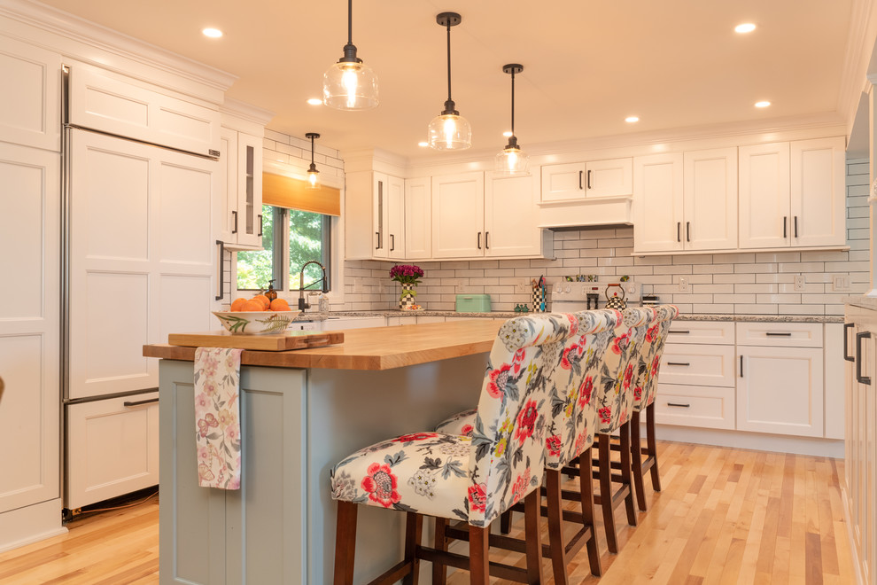 This is an example of a mid-sized transitional l-shaped eat-in kitchen in Boston with a farmhouse sink, shaker cabinets, white cabinets, quartz benchtops, white splashback, ceramic splashback, medium hardwood floors and with island.