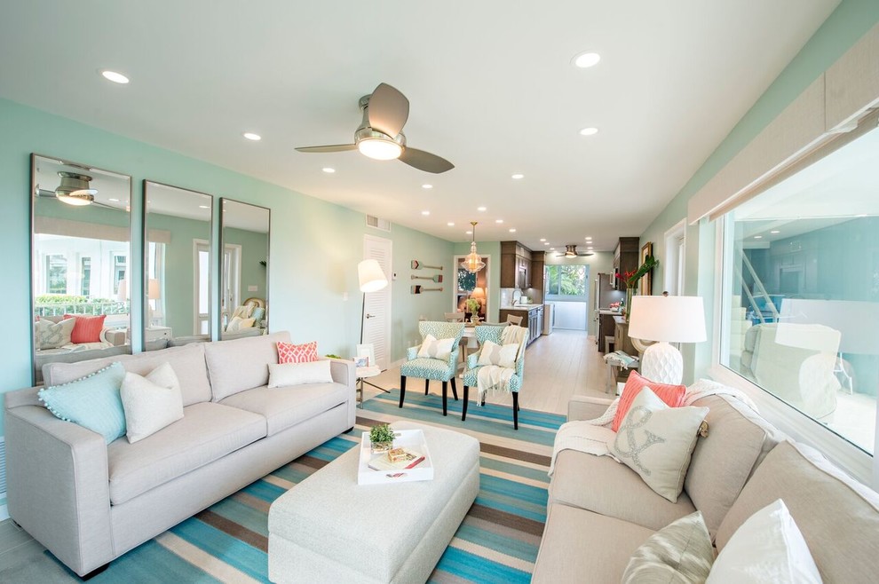 This is an example of a large beach style formal open concept living room in Miami with blue walls, light hardwood floors and beige floor.