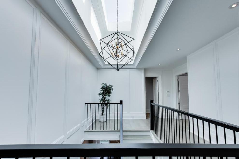 На фото: большой коридор: освещение в стиле неоклассика (современная классика) с белыми стенами, светлым паркетным полом, коричневым полом, многоуровневым потолком и панелями на стенах с