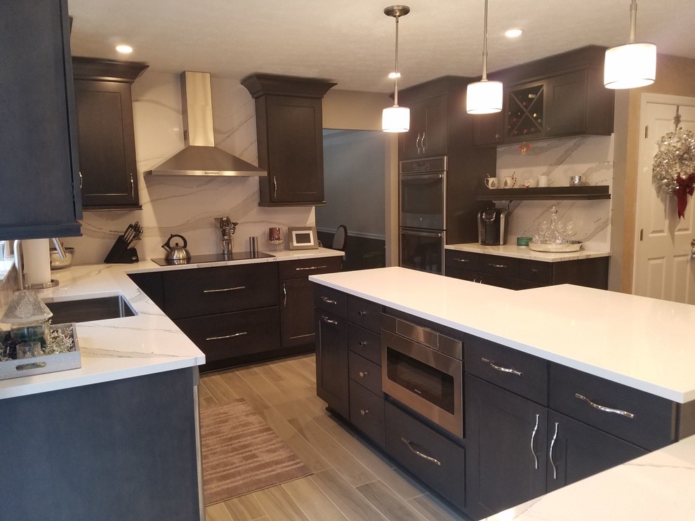 Inspiration for a mid-sized transitional l-shaped porcelain tile and gray floor enclosed kitchen remodel in Other with an undermount sink, raised-panel cabinets, dark wood cabinets, quartz countertops, white backsplash, stone slab backsplash, stainless steel appliances and an island