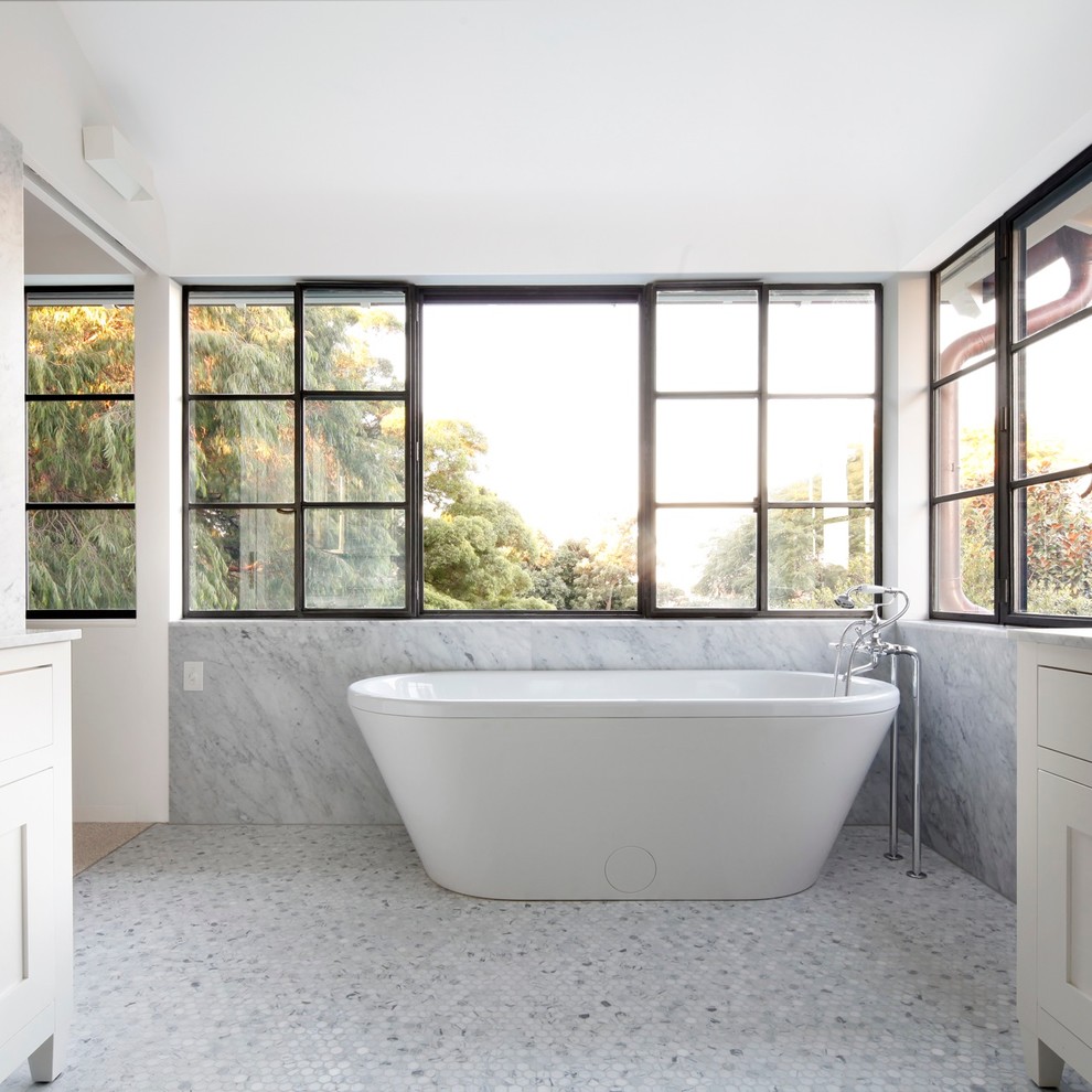 Photo of a large transitional bathroom in Sydney with recessed-panel cabinets, white cabinets, marble benchtops, a freestanding tub and white walls.