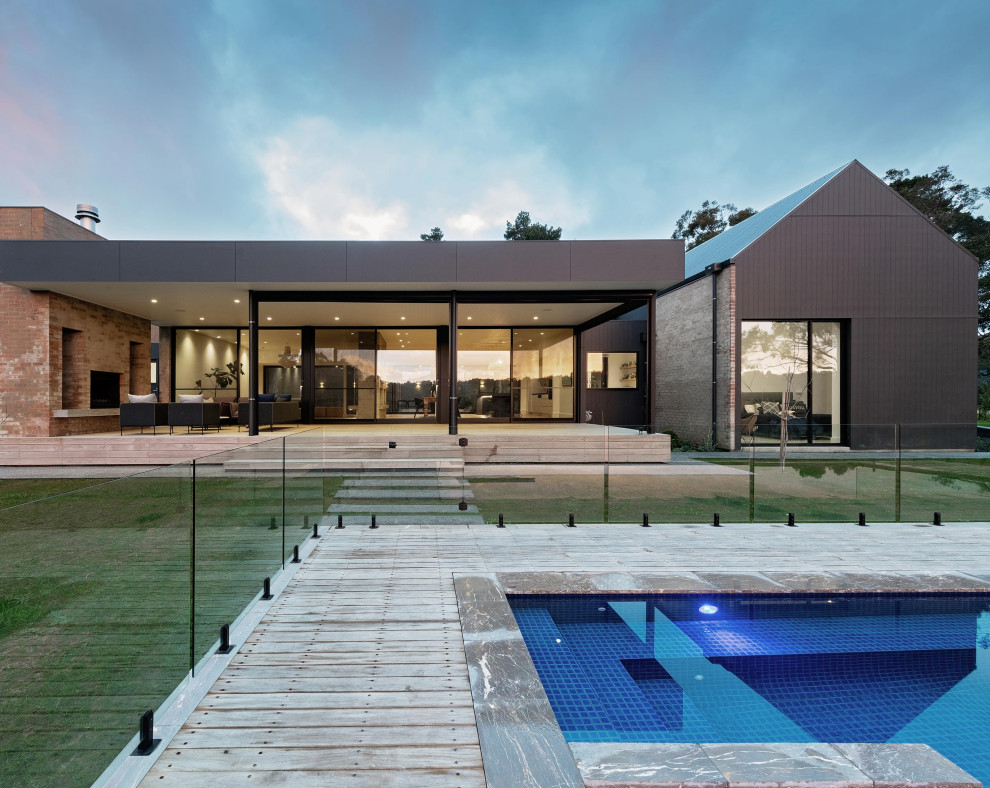 Свежая идея для дизайна: большой прямоугольный ландшафтный бассейн на заднем дворе в стиле модернизм с настилом - отличное фото интерьера