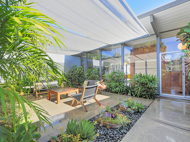Design ideas for a mid-sized midcentury courtyard patio in Orange County with concrete pavers and an awning.