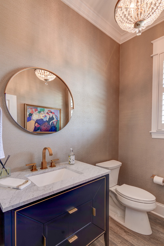 Mid-sized eclectic powder room in Indianapolis with furniture-like cabinets, blue cabinets, a two-piece toilet, beige walls, vinyl floors, a pedestal sink, granite benchtops, brown floor and white benchtops.