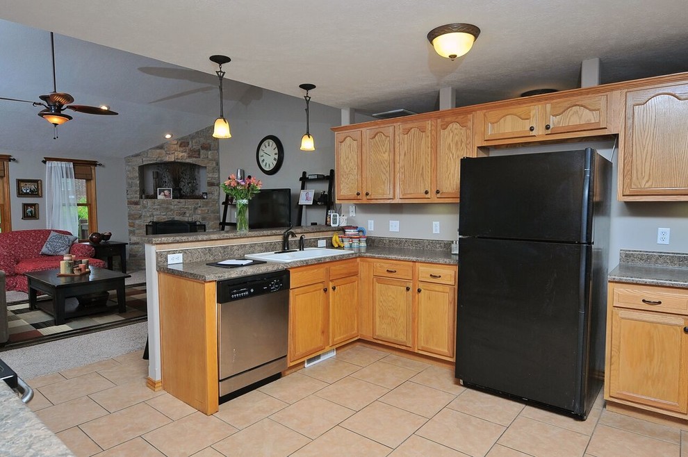 Transitional l-shaped ceramic tile eat-in kitchen photo with a drop-in sink, recessed-panel cabinets, light wood cabinets, granite countertops, brown backsplash, black appliances and no island