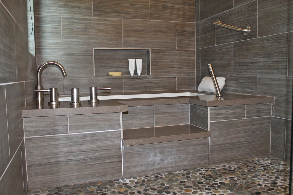 This is an example of a mid-sized contemporary 3/4 bathroom in San Francisco with glass-front cabinets, dark wood cabinets, an undermount tub, a shower/bathtub combo, a two-piece toilet, gray tile, stone tile, white walls, porcelain floors, an undermount sink, engineered quartz benchtops, beige floor, a hinged shower door, green benchtops, a shower seat, a double vanity, a floating vanity and vaulted.