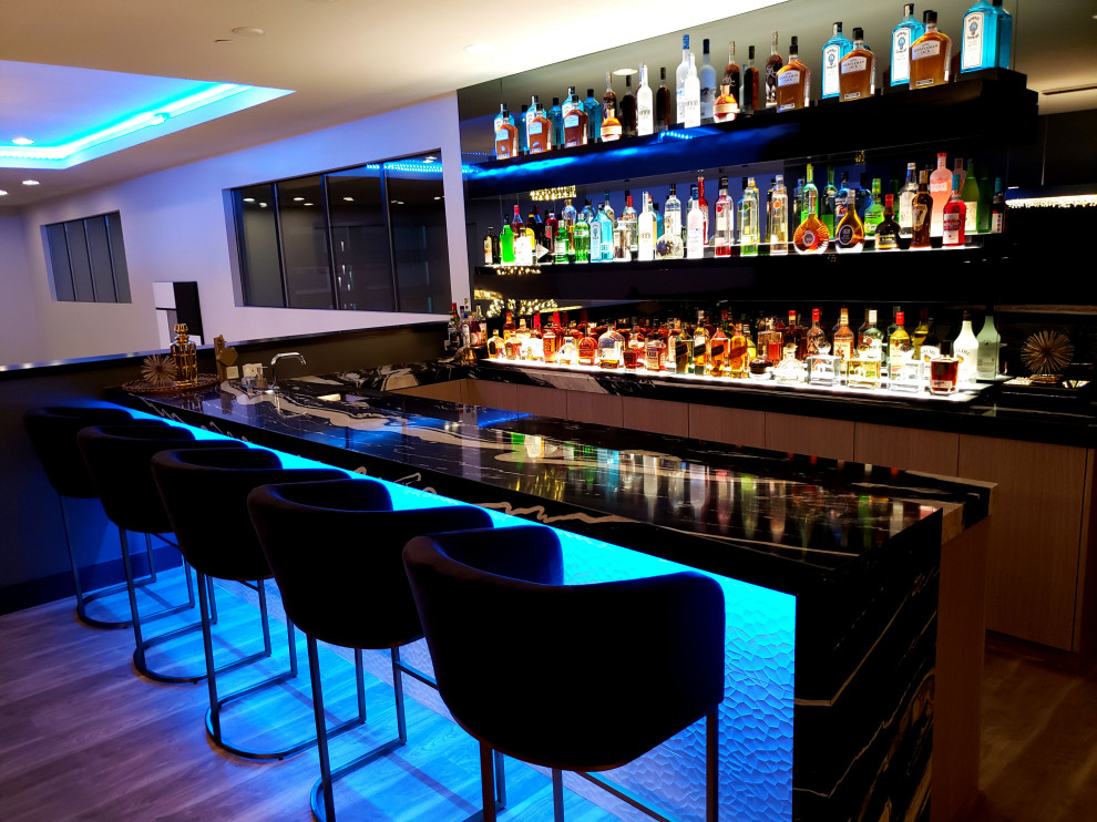 Large modern galley seated home bar in Las Vegas with a drop-in sink, marble benchtops, grey splashback, mirror splashback, porcelain floors, grey floor, multi-coloured benchtop, flat-panel cabinets and grey cabinets.
