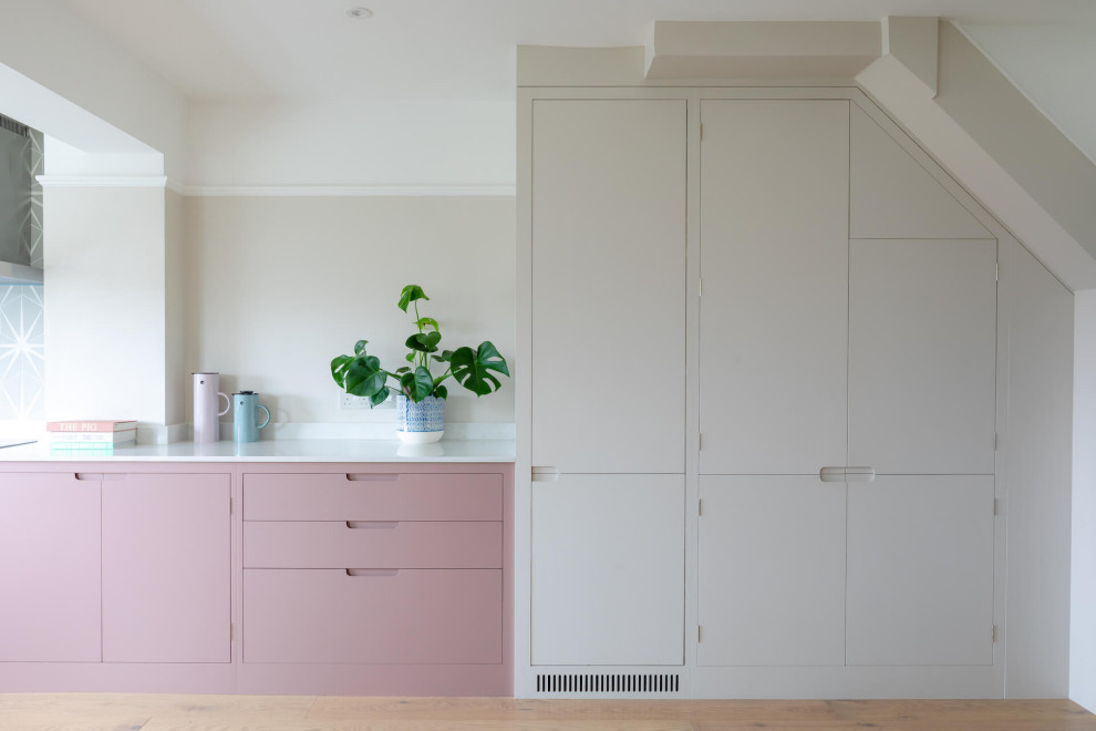 This is an example of a mid-sized scandinavian l-shaped eat-in kitchen in Other with flat-panel cabinets, pink cabinets, quartz benchtops, light hardwood floors, no island and white benchtop.