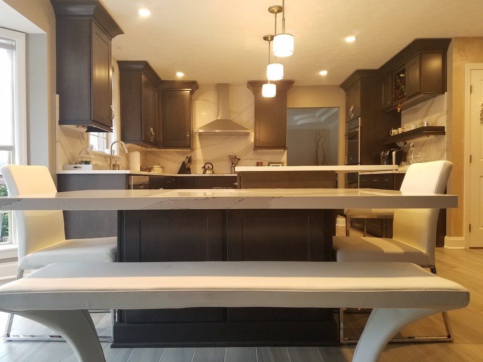 Inspiration for a mid-sized transitional l-shaped porcelain tile and gray floor enclosed kitchen remodel with an undermount sink, raised-panel cabinets, dark wood cabinets, quartz countertops, white backsplash, stone slab backsplash, stainless steel appliances and an island