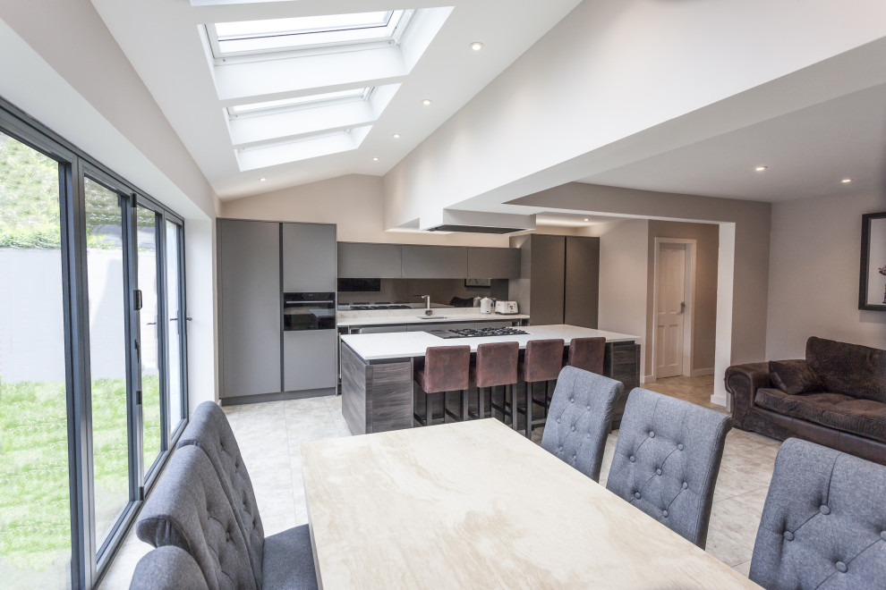 Photo of a mid-sized contemporary single-wall open plan kitchen in Manchester with an undermount sink, flat-panel cabinets, dark wood cabinets, quartzite benchtops, metallic splashback, panelled appliances, vinyl floors, with island, beige floor and white benchtop.