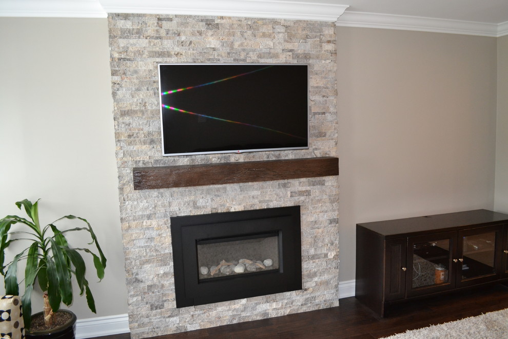 This is an example of a small transitional enclosed family room in Toronto with a library, beige walls, dark hardwood floors, a standard fireplace, a stone fireplace surround and a wall-mounted tv.