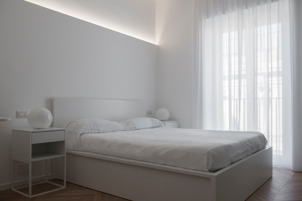 Inspiration for a mid-sized contemporary master bedroom in Rome with white walls, medium hardwood floors and brown floor.
