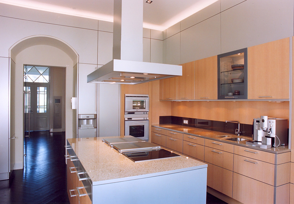 This is an example of a large contemporary l-shaped separate kitchen in Hamburg with a double-bowl sink, flat-panel cabinets, medium wood cabinets, black splashback, glass sheet splashback, white appliances, painted wood floors and with island.
