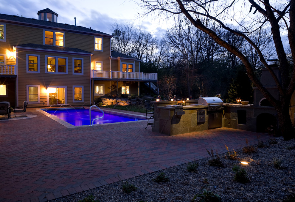 This is an example of a large traditional backyard patio in Minneapolis with an outdoor kitchen and brick pavers.