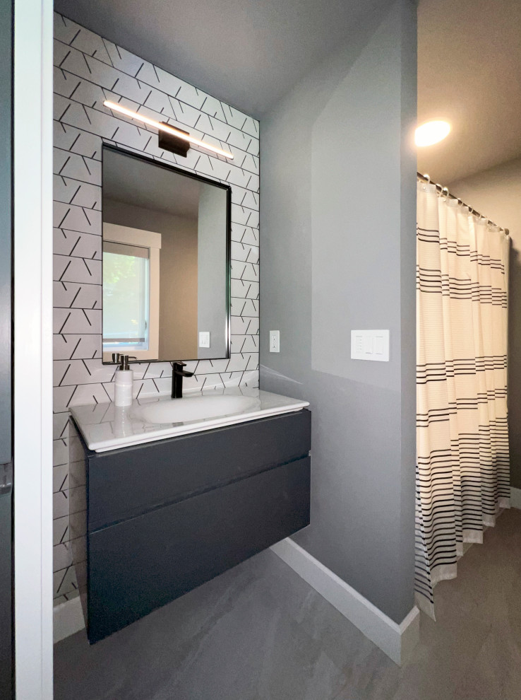 Design ideas for a medium sized contemporary family bathroom in Seattle with flat-panel cabinets, dark wood cabinets, an alcove bath, a shower/bath combination, a two-piece toilet, white tiles, porcelain tiles, blue walls, porcelain flooring, an integrated sink, glass worktops, grey floors, a shower curtain, white worktops, a single sink and a floating vanity unit.