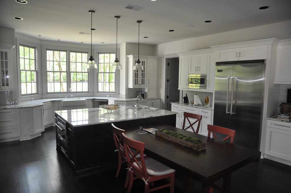 Inspiration for a mid-sized transitional u-shaped dark wood floor and brown floor enclosed kitchen remodel with an undermount sink, shaker cabinets, white cabinets, window backsplash, stainless steel appliances and an island