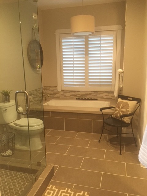Mid-sized transitional 3/4 bathroom in Phoenix with a vessel sink, glass-front cabinets, white cabinets, quartzite benchtops, a drop-in tub, a corner shower, a two-piece toilet, brown tile, ceramic tile, beige walls and ceramic floors.
