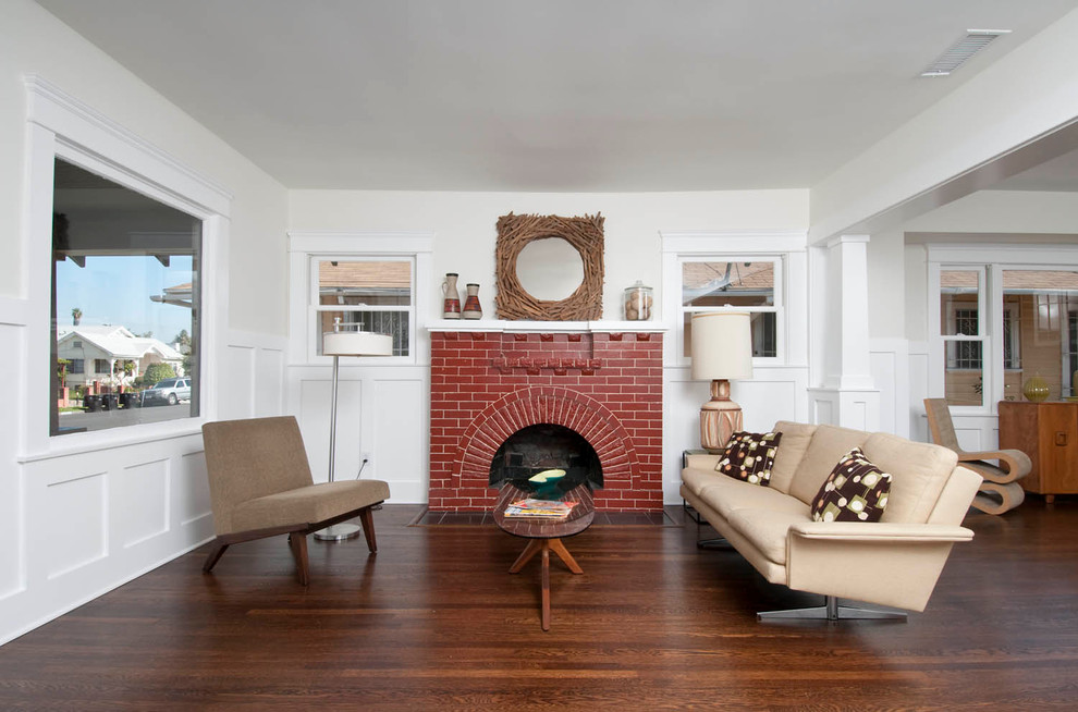 This is an example of a mid-sized arts and crafts open concept living room in Los Angeles with white walls, dark hardwood floors, a standard fireplace and a brick fireplace surround.