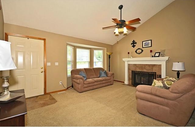 Photo of a traditional open concept living room in Kansas City with beige walls, carpet, a standard fireplace, a tile fireplace surround and no tv.