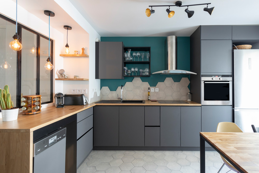 This is an example of a contemporary l-shaped eat-in kitchen in Paris with a drop-in sink, flat-panel cabinets, grey cabinets, wood benchtops, stainless steel appliances, no island, grey floor and brown benchtop.