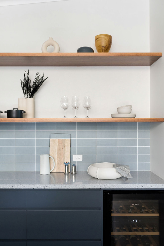 This is an example of a mid-sized contemporary l-shaped kitchen pantry in Canberra - Queanbeyan with an undermount sink, flat-panel cabinets, blue cabinets, terrazzo benchtops, blue splashback, subway tile splashback, black appliances, laminate floors, with island, beige floor, blue benchtop and vaulted.